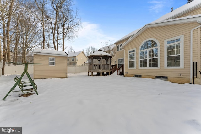 snowy yard featuring a storage shed, a gazebo, and a deck