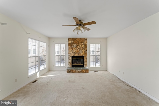 unfurnished living room with ceiling fan, light carpet, a fireplace, and a wealth of natural light