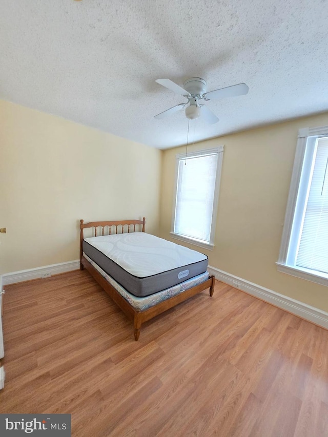 unfurnished bedroom with a textured ceiling, ceiling fan, and light hardwood / wood-style flooring