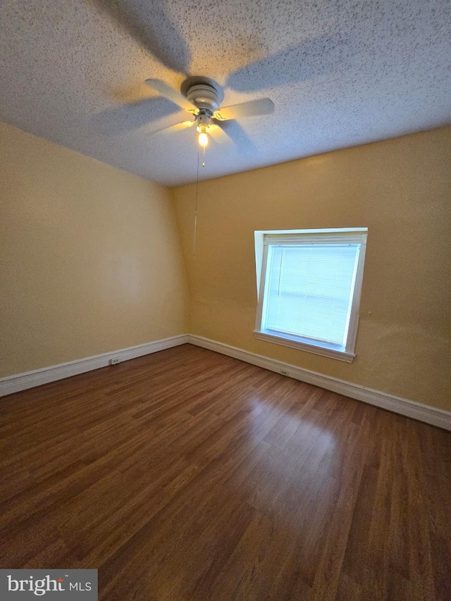 spare room with a textured ceiling, ceiling fan, and dark hardwood / wood-style floors