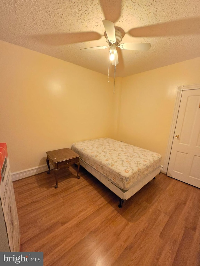 unfurnished bedroom with hardwood / wood-style floors, a textured ceiling, and ceiling fan