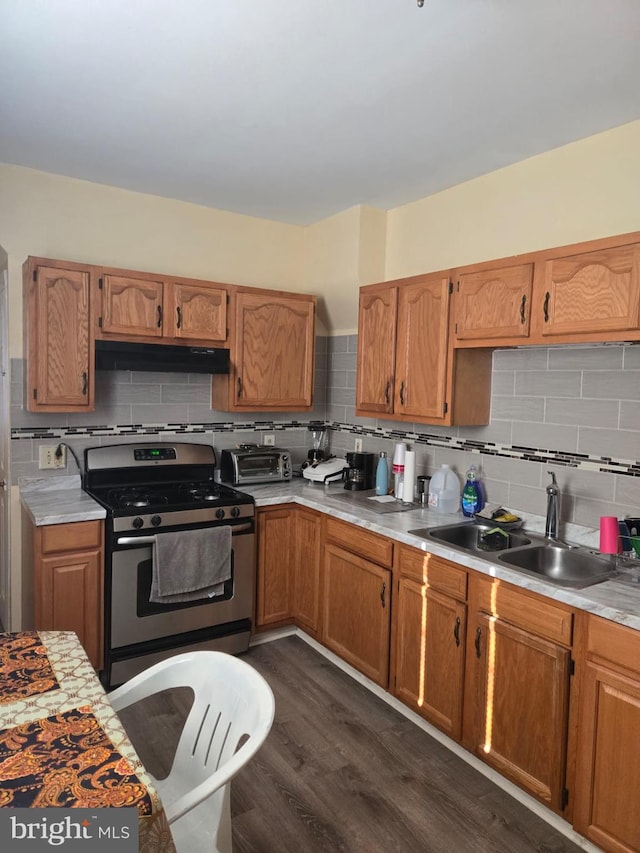 kitchen featuring dark hardwood / wood-style flooring, stainless steel range with gas stovetop, tasteful backsplash, and sink