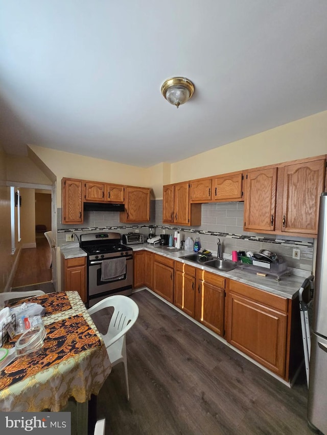 kitchen with sink, dark hardwood / wood-style floors, tasteful backsplash, and appliances with stainless steel finishes