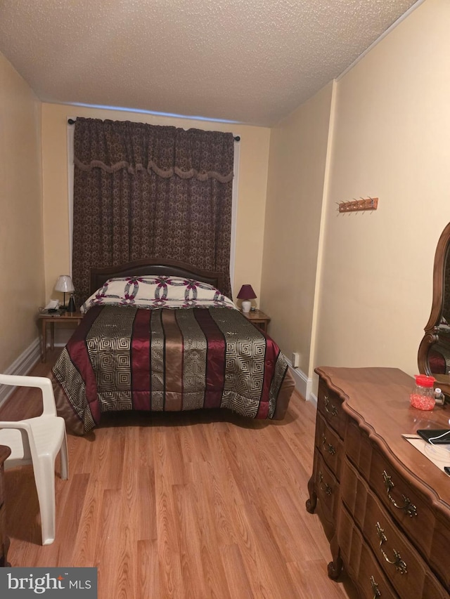 bedroom with a textured ceiling and light hardwood / wood-style flooring