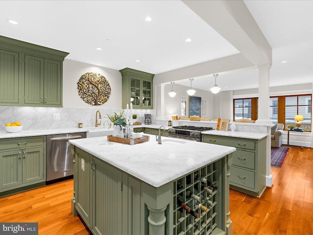 kitchen with an island with sink, stainless steel appliances, and green cabinets