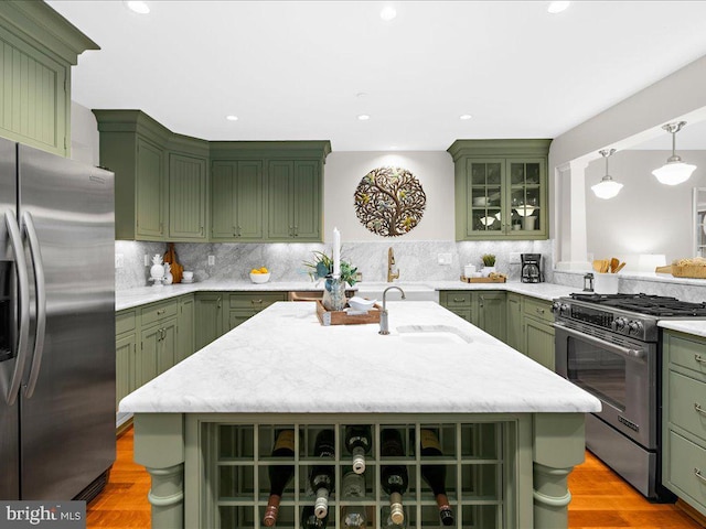 kitchen featuring green cabinetry, a center island with sink, and appliances with stainless steel finishes