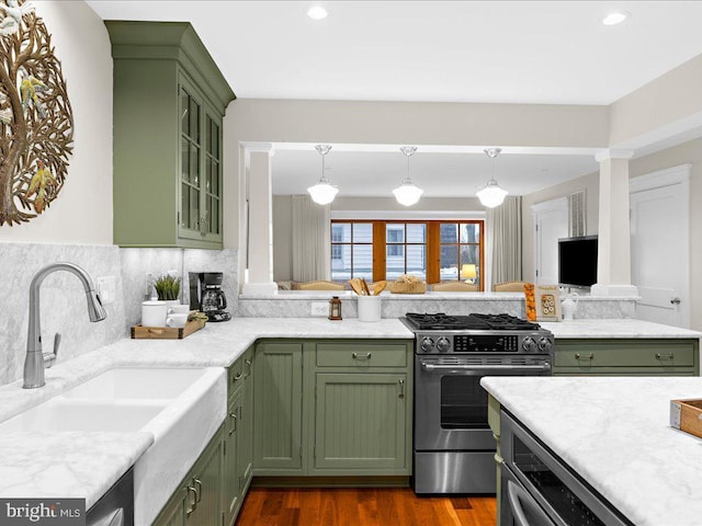 kitchen with green cabinetry, stainless steel gas stove, sink, and pendant lighting