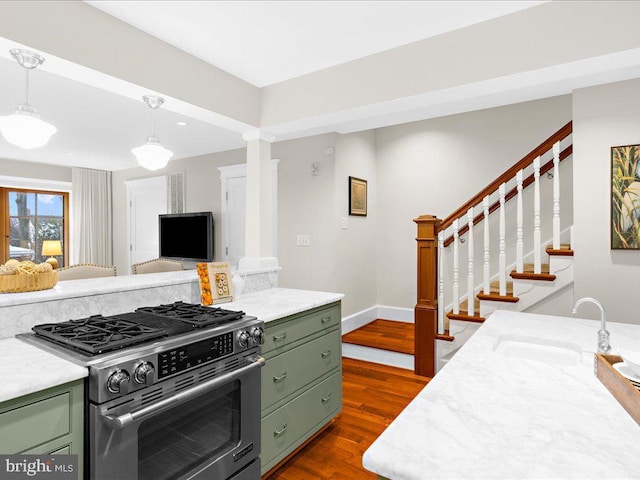 kitchen featuring sink, dark hardwood / wood-style flooring, green cabinetry, stainless steel range with gas cooktop, and ornate columns