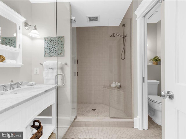 bathroom featuring tile patterned floors, vanity, a shower with shower door, and toilet