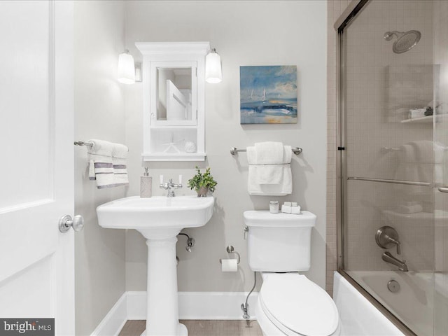 bathroom featuring shower / bath combination with glass door and toilet