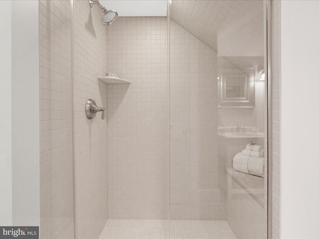 bathroom with a tile shower and lofted ceiling