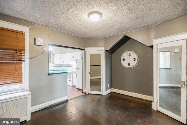 unfurnished room with a textured ceiling, radiator, and dark hardwood / wood-style floors