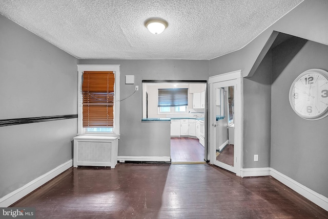 interior space with a textured ceiling and dark hardwood / wood-style flooring