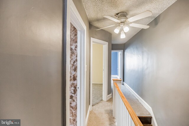 corridor featuring a textured ceiling and light colored carpet