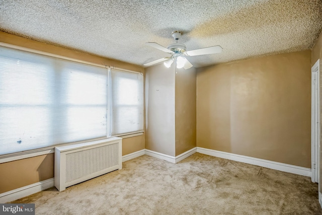 unfurnished room with radiator, a textured ceiling, ceiling fan, and light colored carpet