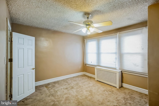 carpeted empty room with radiator, a textured ceiling, and ceiling fan