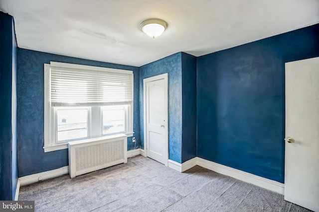 unfurnished bedroom with a closet, radiator heating unit, and light carpet