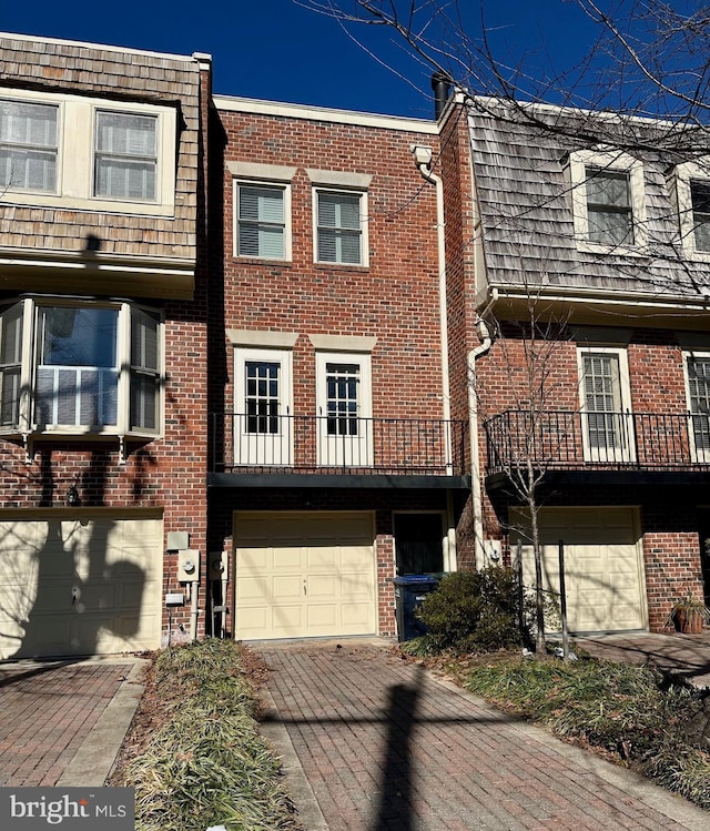 townhome / multi-family property featuring a garage, decorative driveway, and brick siding