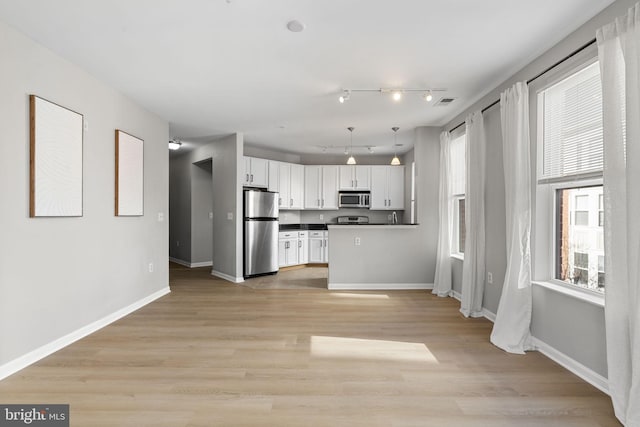 kitchen with white cabinetry, appliances with stainless steel finishes, light wood-type flooring, and pendant lighting