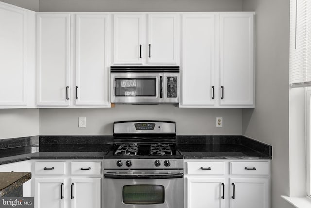 kitchen with white cabinetry, stainless steel appliances, and dark stone counters