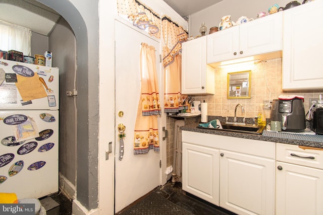 kitchen with white refrigerator, white cabinetry, sink, and backsplash