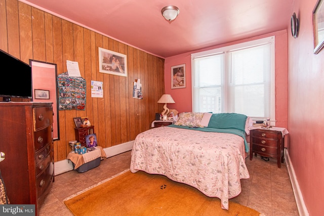 bedroom with wood walls and light tile patterned floors