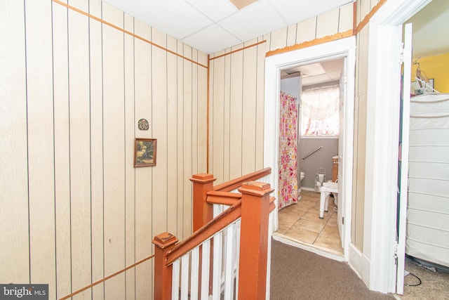 hallway with wood walls and a drop ceiling