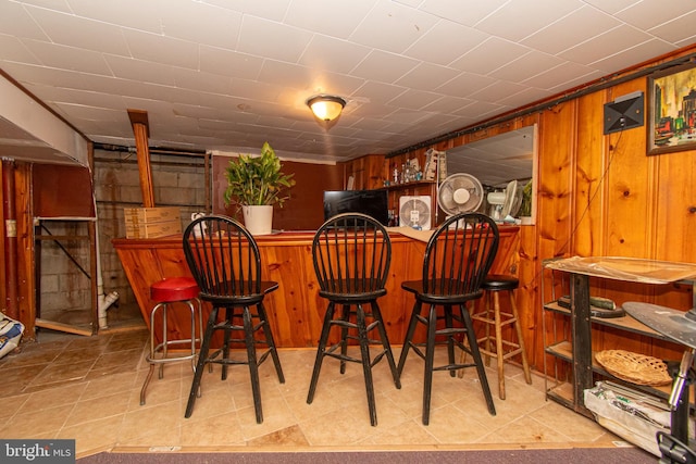 bar featuring wood walls and crown molding