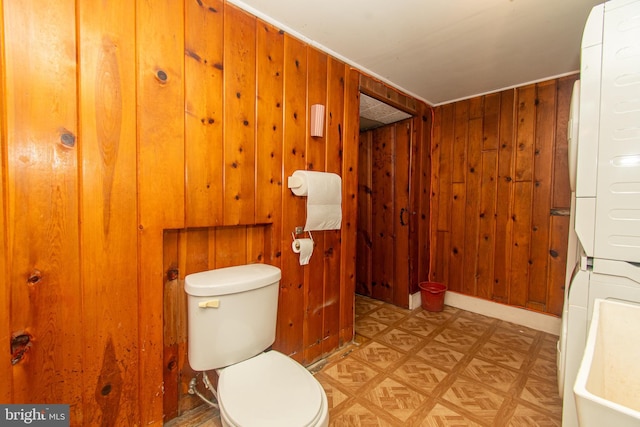 bathroom featuring toilet and wood walls