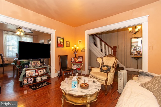 living room with ceiling fan with notable chandelier and hardwood / wood-style flooring