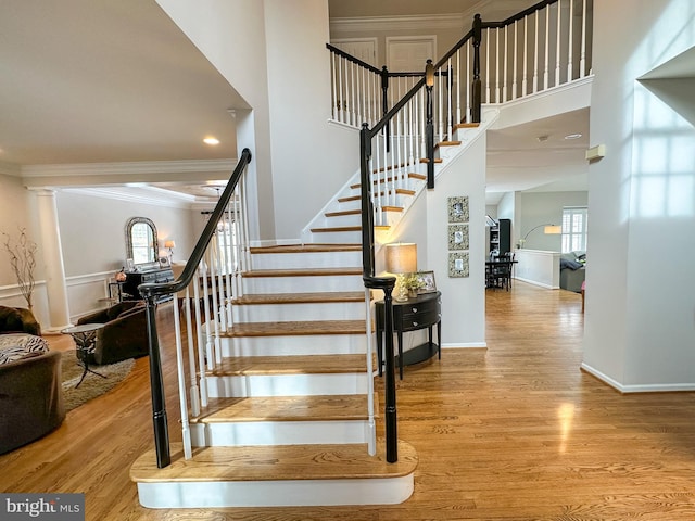 stairs with hardwood / wood-style flooring and ornamental molding