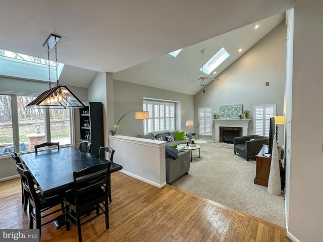 dining area featuring a skylight, high vaulted ceiling, and wood-type flooring