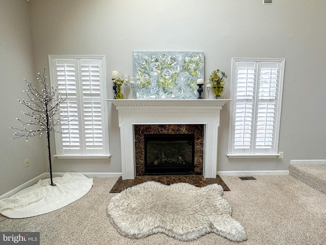 sitting room featuring a wealth of natural light, a high end fireplace, and carpet flooring