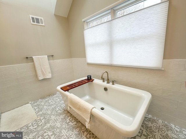 bathroom featuring a bathing tub, tile patterned flooring, and tile walls