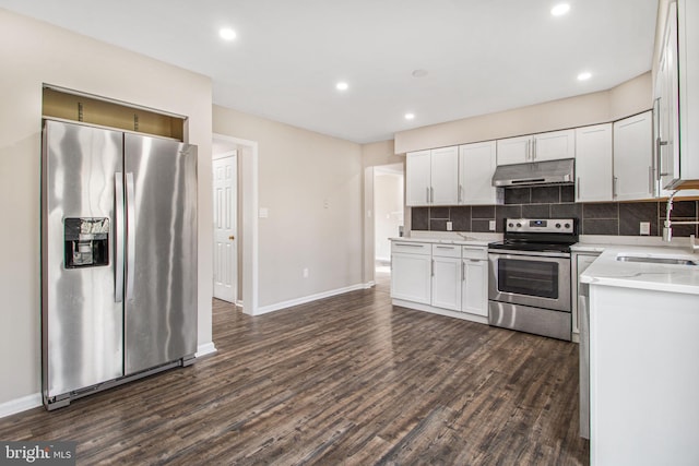 kitchen with stainless steel appliances, sink, white cabinets, decorative backsplash, and dark wood-type flooring