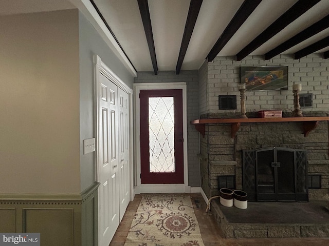 foyer entrance featuring beam ceiling and a stone fireplace