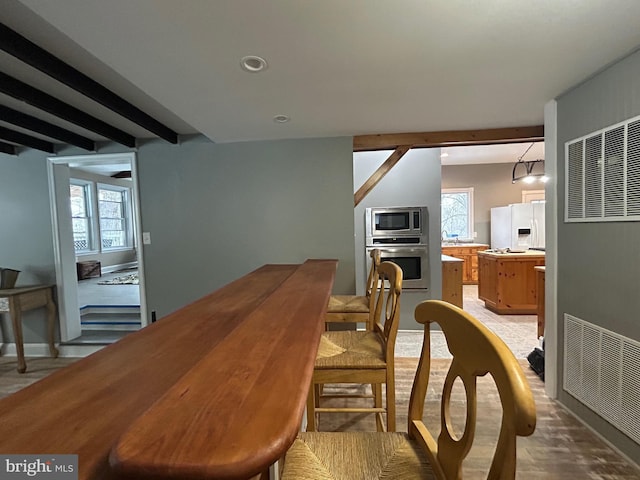 dining area featuring hardwood / wood-style floors and beam ceiling