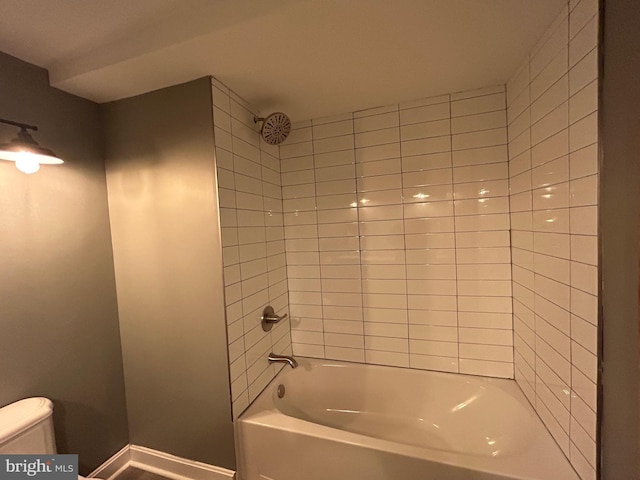 bathroom featuring tiled shower / bath combo and toilet