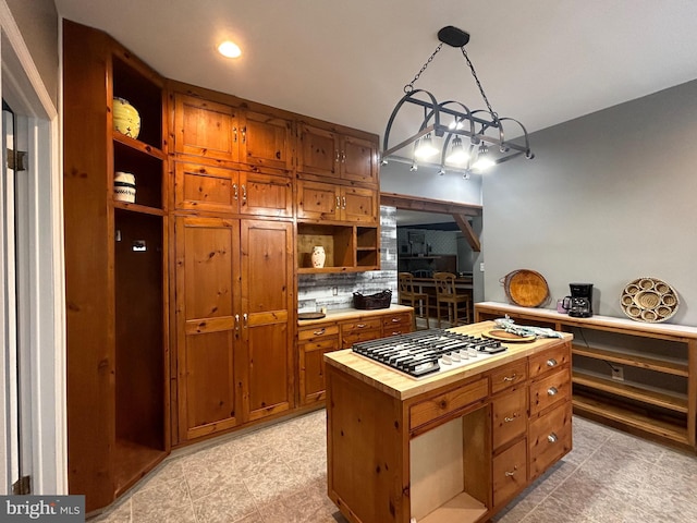 kitchen with decorative light fixtures, decorative backsplash, stainless steel gas stovetop, and a center island