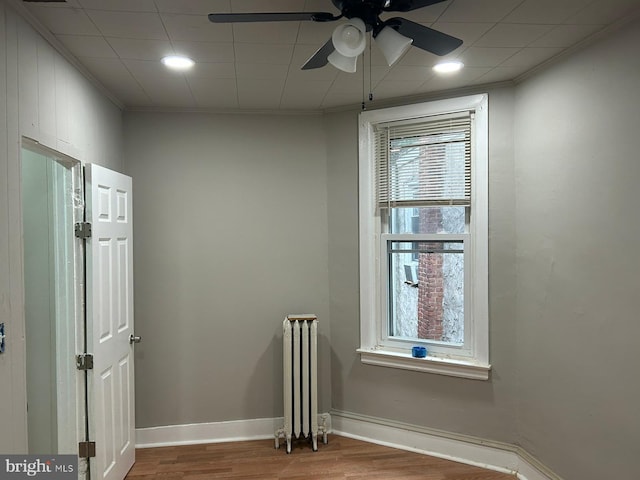 unfurnished room with ceiling fan, radiator heating unit, and hardwood / wood-style floors