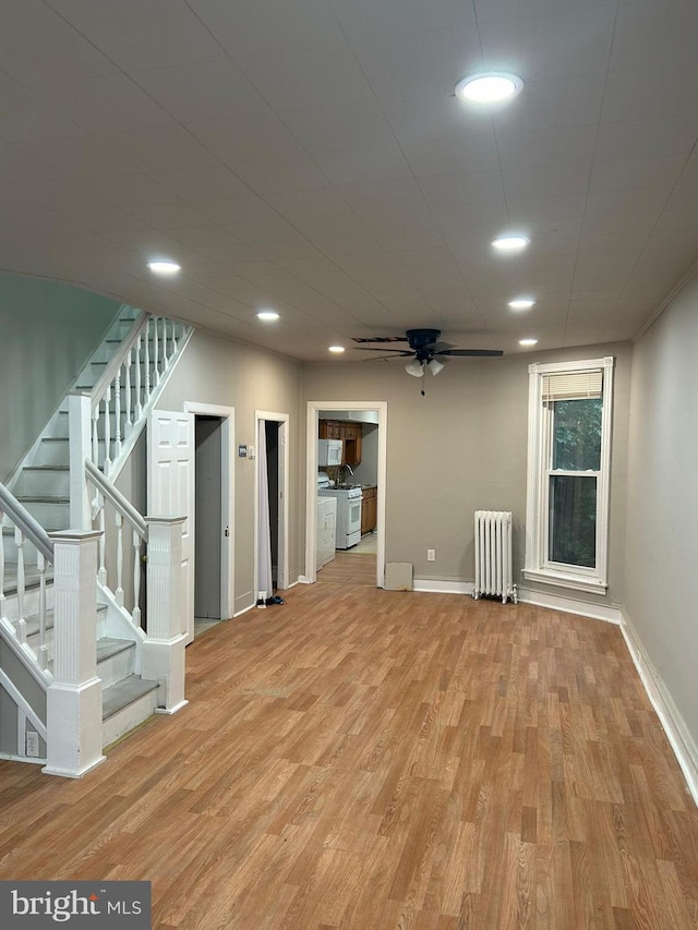 basement with light hardwood / wood-style floors, ceiling fan, and radiator