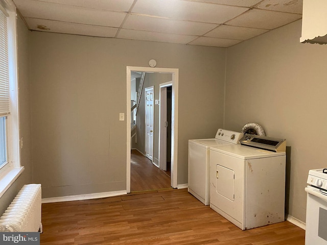 clothes washing area with light hardwood / wood-style floors, washer and clothes dryer, and radiator