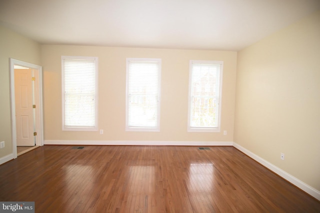 empty room with a healthy amount of sunlight and wood-type flooring