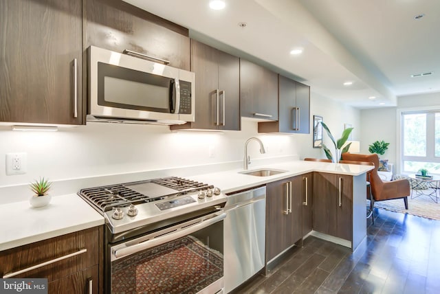 kitchen featuring sink, dark hardwood / wood-style flooring, dark brown cabinetry, kitchen peninsula, and stainless steel appliances