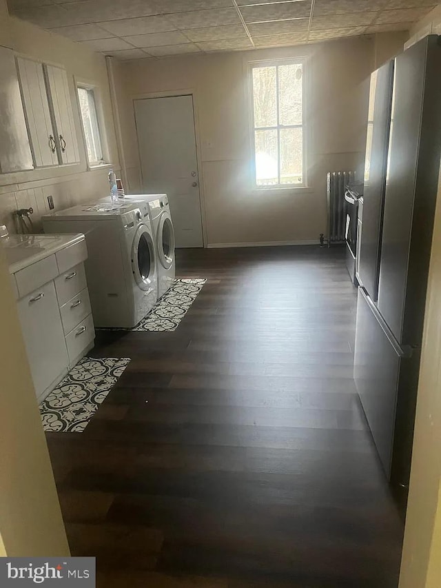 laundry area featuring radiator heating unit, washer and dryer, dark wood-type flooring, cabinets, and sink