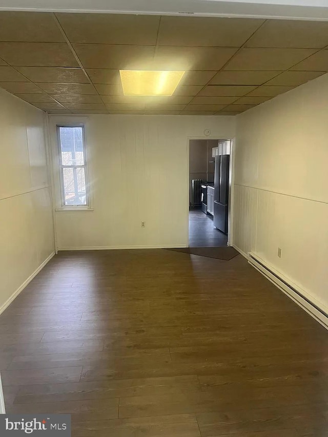 unfurnished room with dark hardwood / wood-style flooring and a baseboard radiator