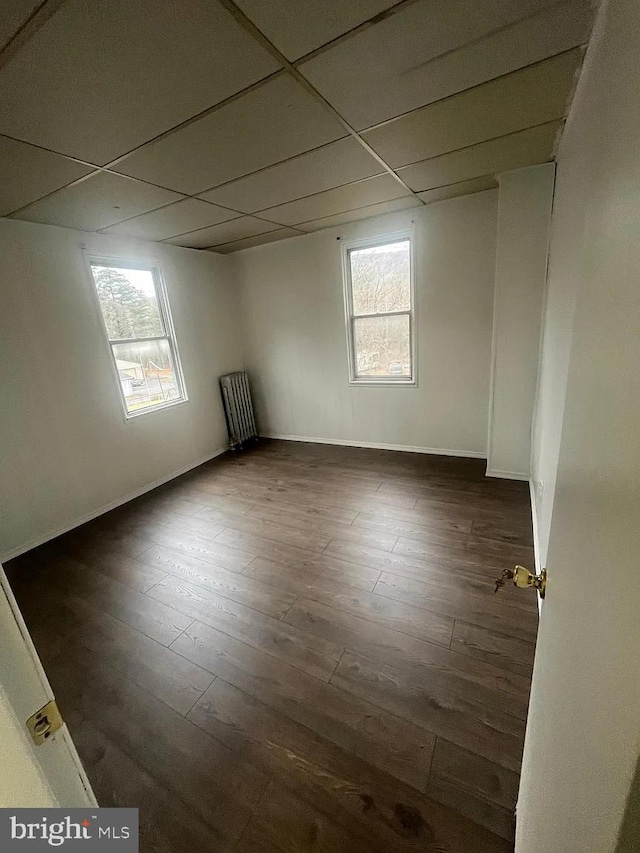 unfurnished room featuring radiator heating unit, a paneled ceiling, and dark hardwood / wood-style flooring