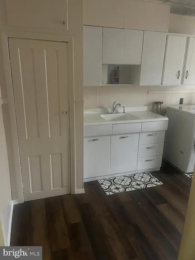 kitchen featuring sink, white cabinets, dark hardwood / wood-style flooring, and washer / dryer