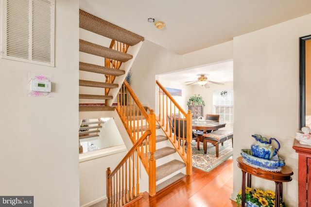 stairs featuring a ceiling fan, visible vents, and wood finished floors