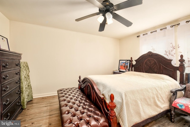 bedroom with a ceiling fan, baseboards, and wood finished floors